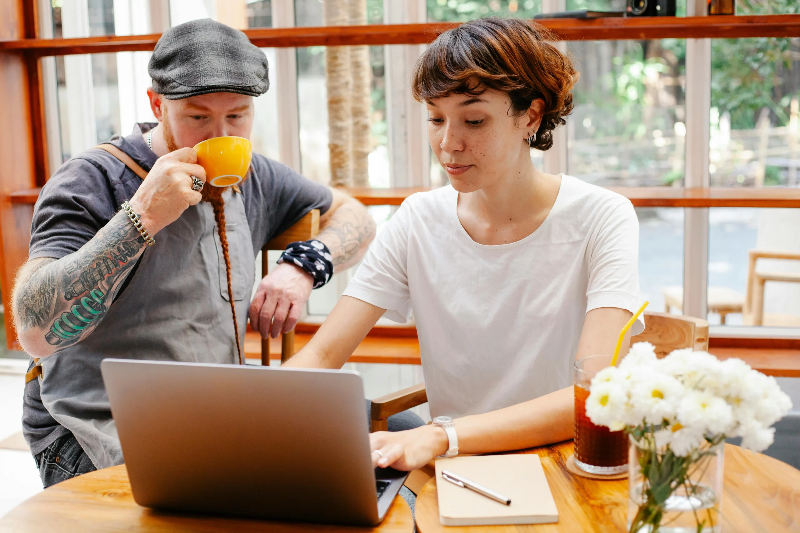 two business owners drink coffee while working on their laptop